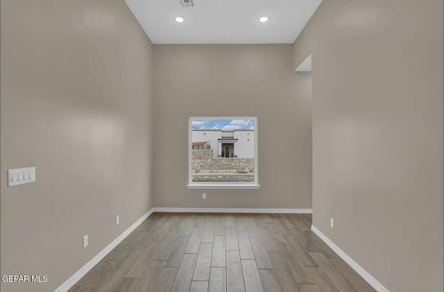 empty room featuring light wood finished floors, baseboards, and recessed lighting