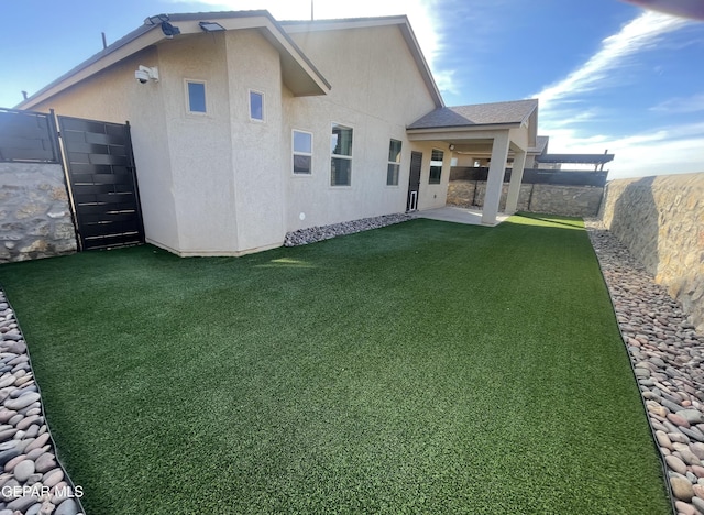 back of property with a fenced backyard, a lawn, and stucco siding