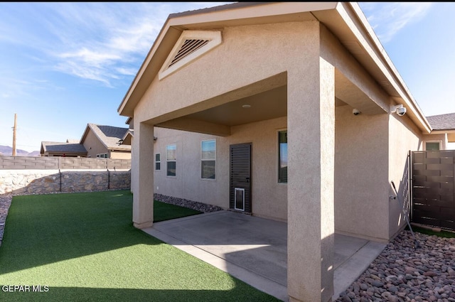 back of house with a lawn, fence, a patio, and stucco siding