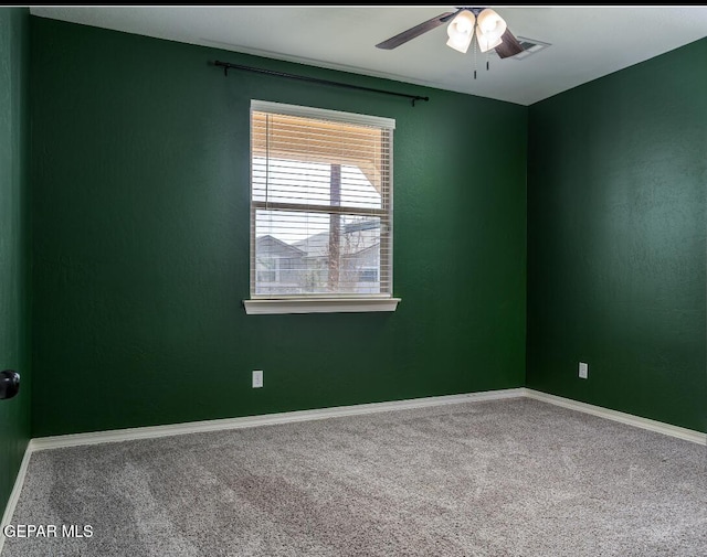 carpeted empty room with ceiling fan and baseboards