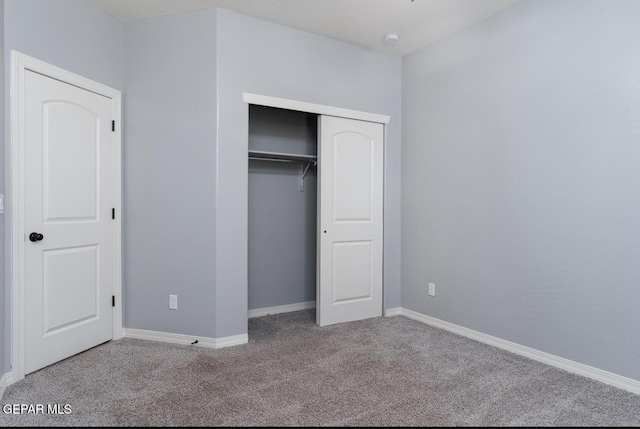 unfurnished bedroom with baseboards, a closet, and light colored carpet