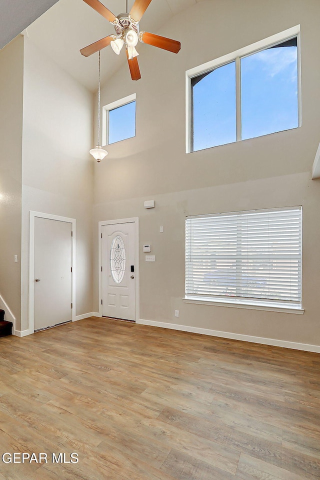 foyer featuring stairs, baseboards, a ceiling fan, and light wood-style floors