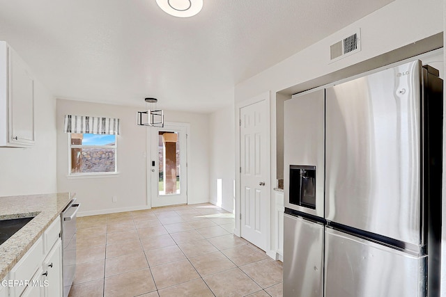 kitchen with light stone counters, visible vents, white cabinetry, hanging light fixtures, and appliances with stainless steel finishes