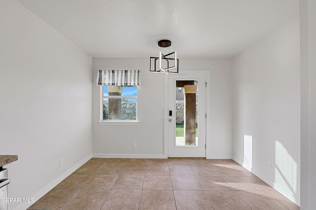 unfurnished dining area featuring light tile patterned floors, baseboards, and an inviting chandelier