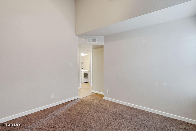 empty room featuring washer / dryer, visible vents, light carpet, and baseboards