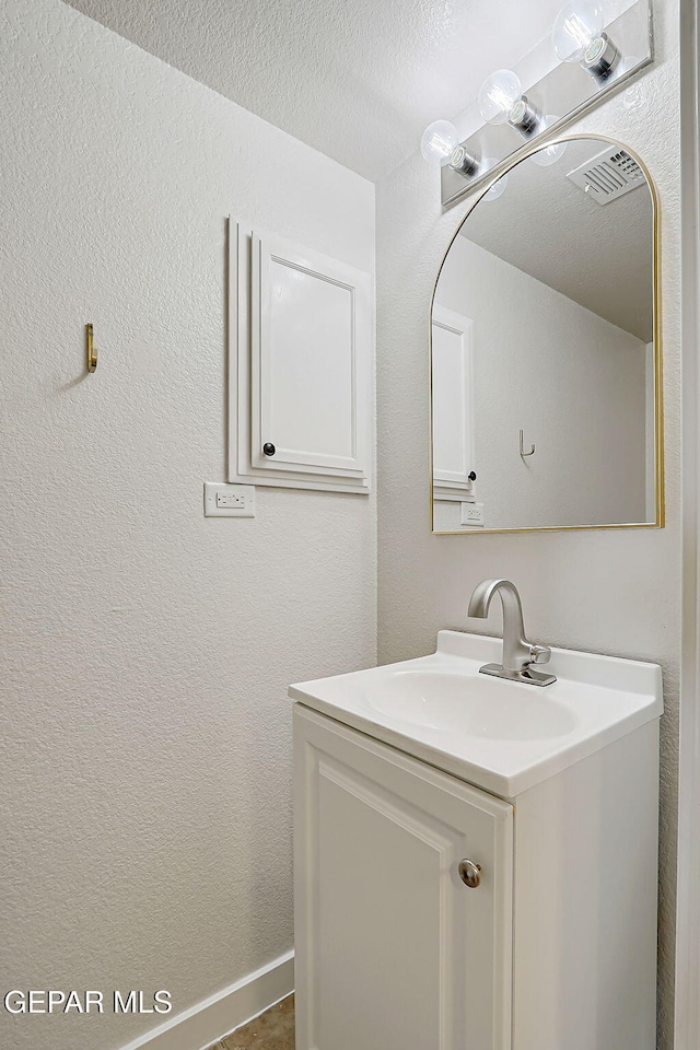 bathroom with a textured ceiling, a textured wall, visible vents, and vanity