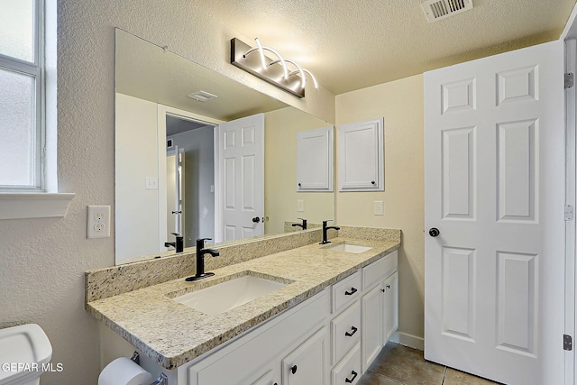 bathroom with visible vents, a sink, and a textured ceiling