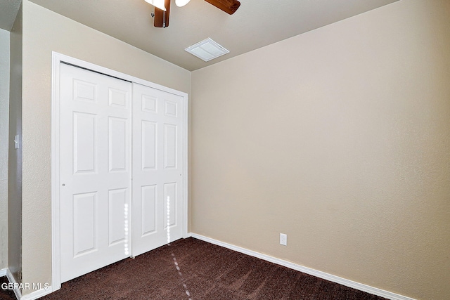 unfurnished bedroom featuring dark colored carpet, a closet, visible vents, a ceiling fan, and baseboards