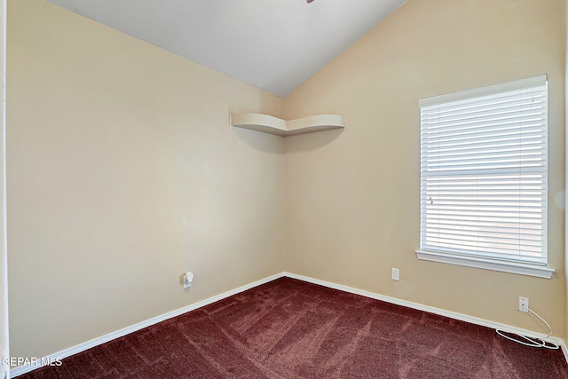 carpeted spare room featuring vaulted ceiling and baseboards