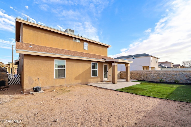 rear view of property with a shingled roof, fence, a lawn, stucco siding, and a patio area