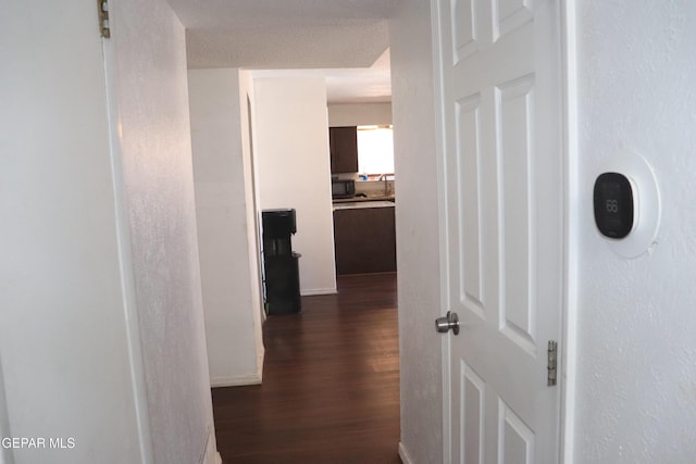 hall with dark wood-style floors and a textured wall