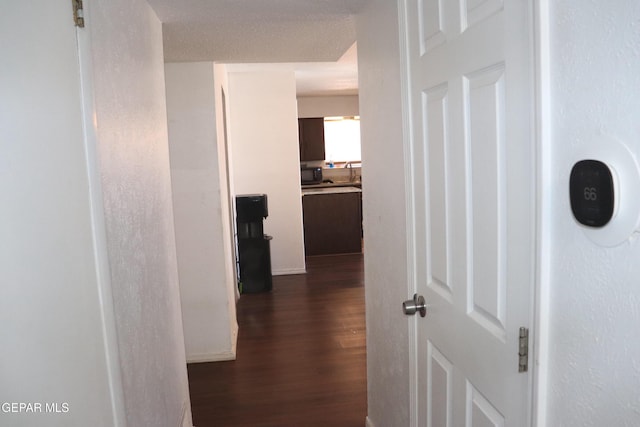 corridor featuring dark wood-style floors and a sink