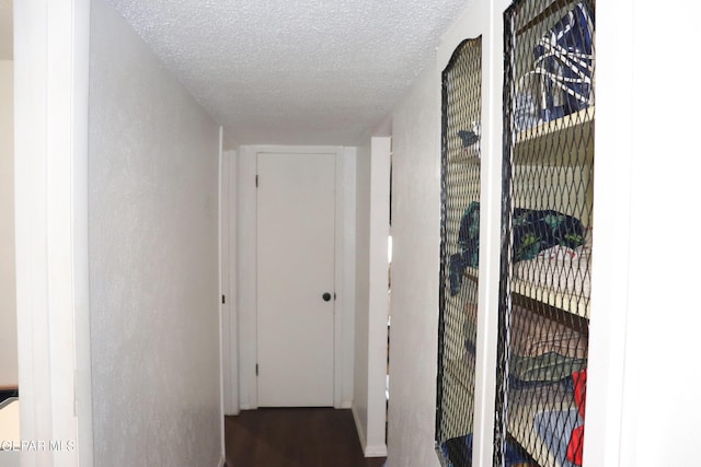 hallway with a textured ceiling and a textured wall