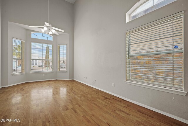 spare room with baseboards, plenty of natural light, a ceiling fan, and wood finished floors