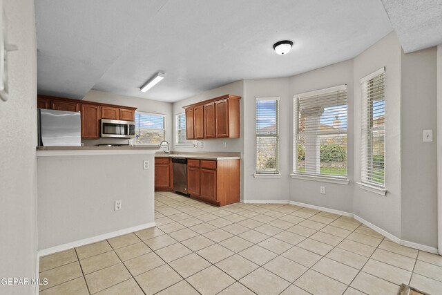 kitchen with light tile patterned floors, stainless steel appliances, light countertops, and baseboards