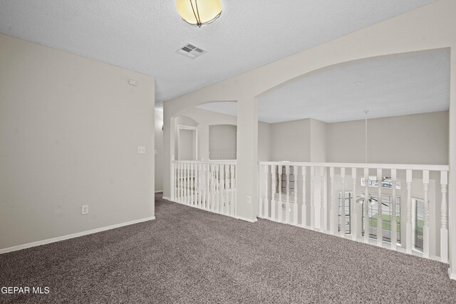 carpeted spare room with baseboards, visible vents, and a textured ceiling