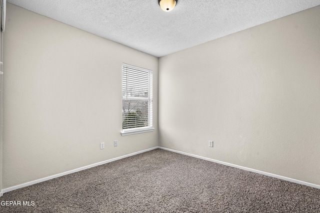 empty room with carpet, a textured ceiling, and baseboards