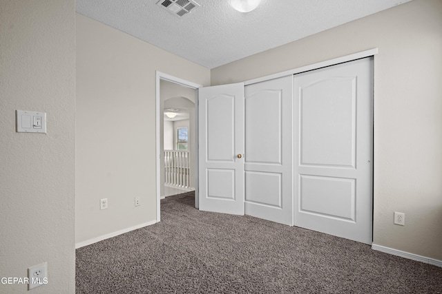 unfurnished bedroom featuring baseboards, visible vents, a textured wall, a textured ceiling, and carpet floors