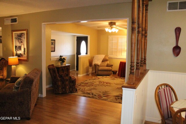 living room with a ceiling fan, wood finished floors, and visible vents