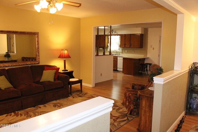 living room featuring baseboards, ceiling fan, and light wood-type flooring