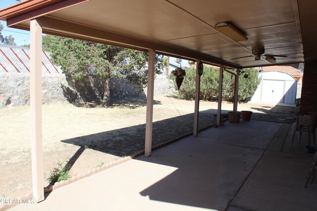 view of patio / terrace with an outdoor structure, a ceiling fan, a shed, and fence