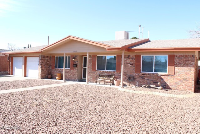 single story home with roof with shingles, brick siding, a garage, covered porch, and driveway