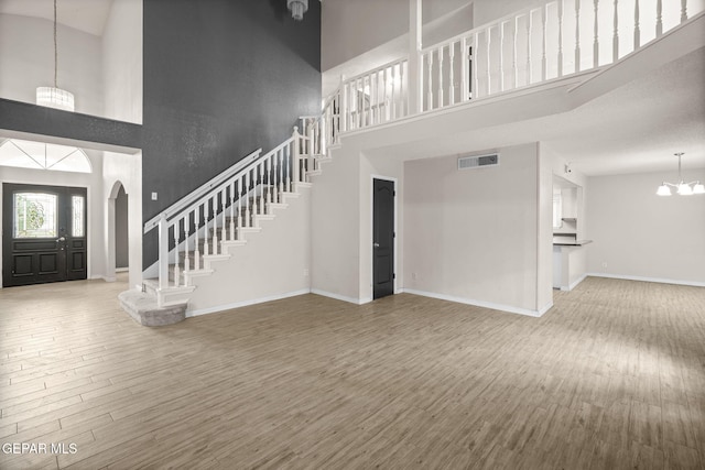 foyer featuring a chandelier, stairway, a towering ceiling, and wood finished floors