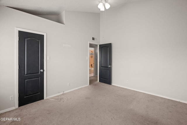 empty room featuring high vaulted ceiling, light colored carpet, visible vents, and baseboards