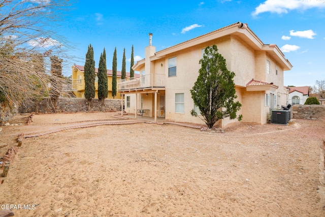 back of house featuring a patio, cooling unit, a balcony, fence, and stucco siding