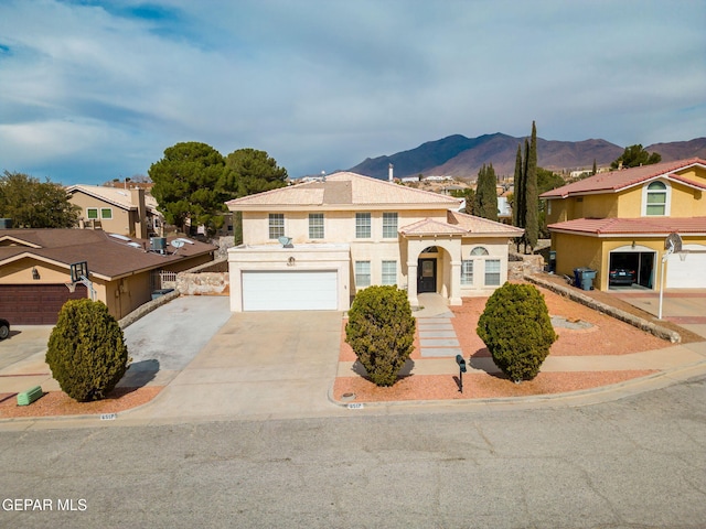 view of front facade with concrete driveway, an attached garage, a mountain view, and stucco siding