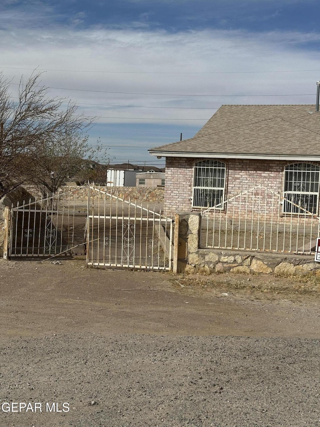 view of front facade with brick siding, roof with shingles, and a fenced front yard