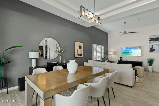 dining room with light wood finished floors, visible vents, a towering ceiling, a ceiling fan, and baseboards