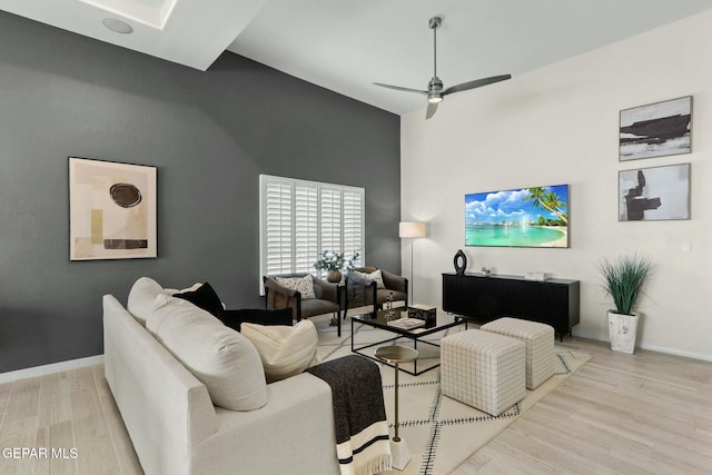 living area with baseboards, ceiling fan, and light wood finished floors