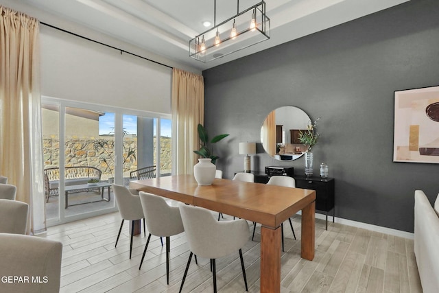 dining area featuring baseboards, a towering ceiling, a tray ceiling, wood finish floors, and recessed lighting