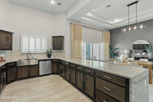 kitchen with visible vents, a raised ceiling, stainless steel dishwasher, pendant lighting, and a sink