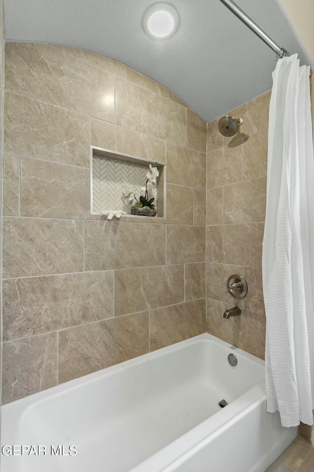 full bathroom with a textured ceiling and shower / bath combination with curtain