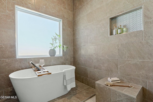 full bath featuring a soaking tub and tile walls