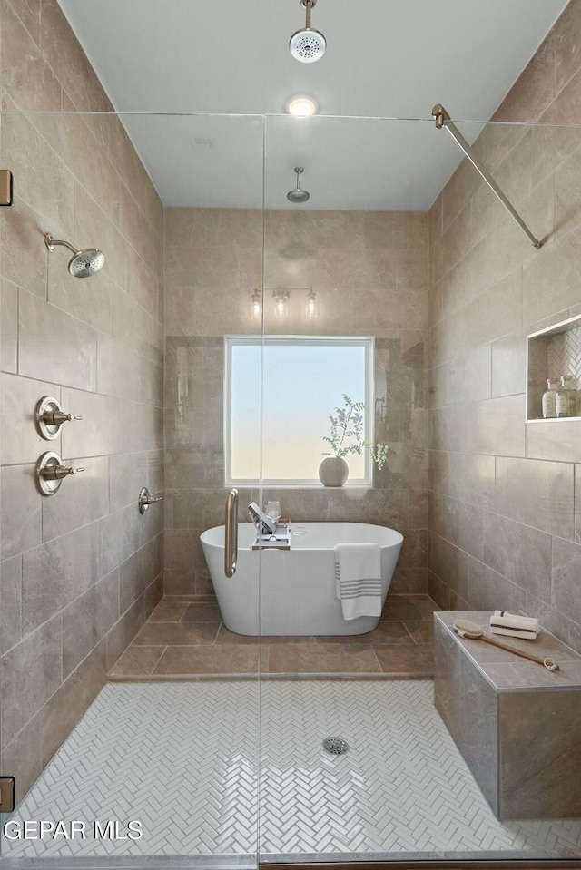 bathroom with tile patterned flooring, tiled shower, a freestanding bath, and tile walls