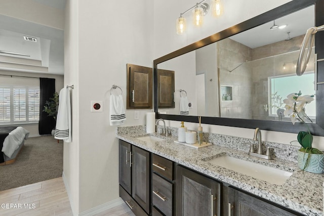 full bathroom with ensuite bathroom, a sink, visible vents, and a tile shower