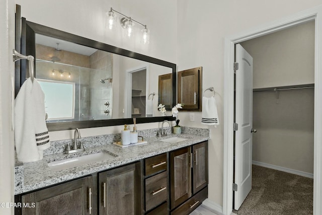 full bathroom featuring double vanity, a spacious closet, a tile shower, and a sink