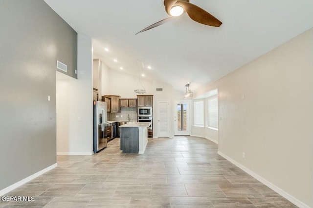 kitchen featuring stainless steel appliances, a kitchen island, open floor plan, light countertops, and brown cabinets