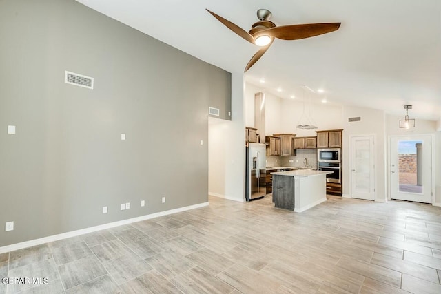 kitchen featuring pendant lighting, light countertops, appliances with stainless steel finishes, open floor plan, and a kitchen island