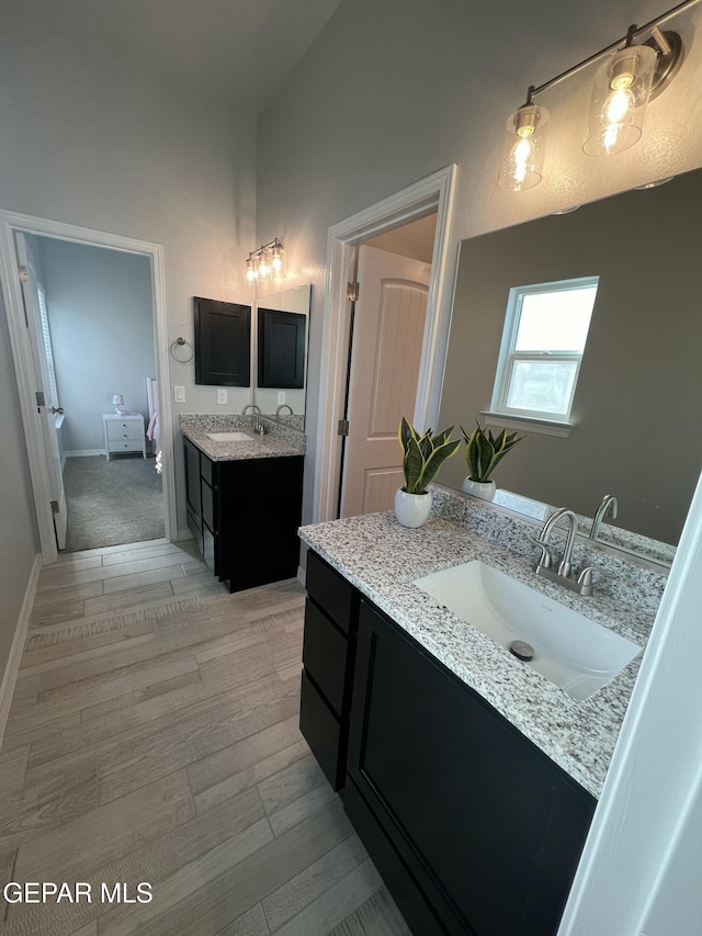 ensuite bathroom with baseboards, two vanities, a sink, and ensuite bathroom