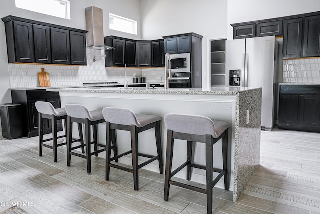 3853 Surmise St, El Paso, TX 79938 - kitchen with island exhaust hood, stainless steel appliances, a towering ceiling, dark cabinetry, and decorative backsplash