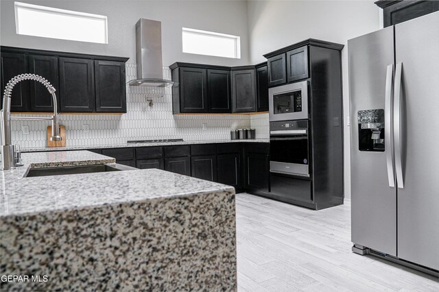 3853 Surmise St, El Paso, TX 79938 - kitchen featuring appliances with stainless steel finishes, range hood, backsplash, dark cabinets, and a towering ceiling