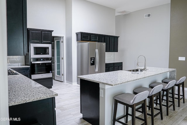 3853 Surmise St, El Paso, TX 79938 - kitchen with oven, built in microwave, stainless steel fridge, dark cabinetry, and light wood-style floors