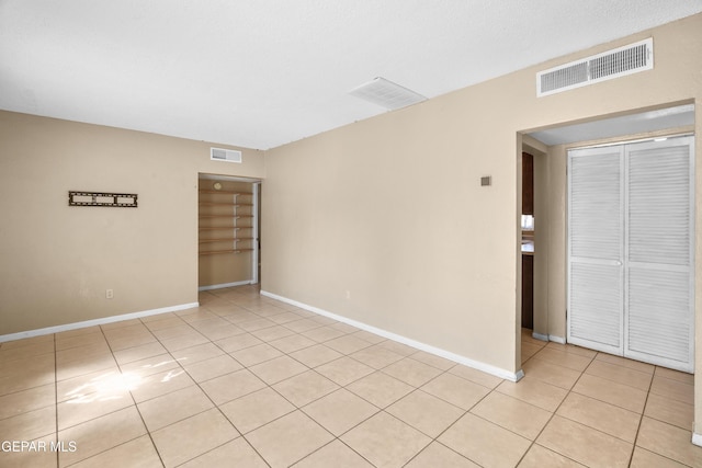 unfurnished room featuring light tile patterned floors, baseboards, and visible vents