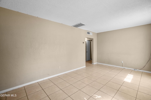 spare room with visible vents, a textured ceiling, and light tile patterned floors