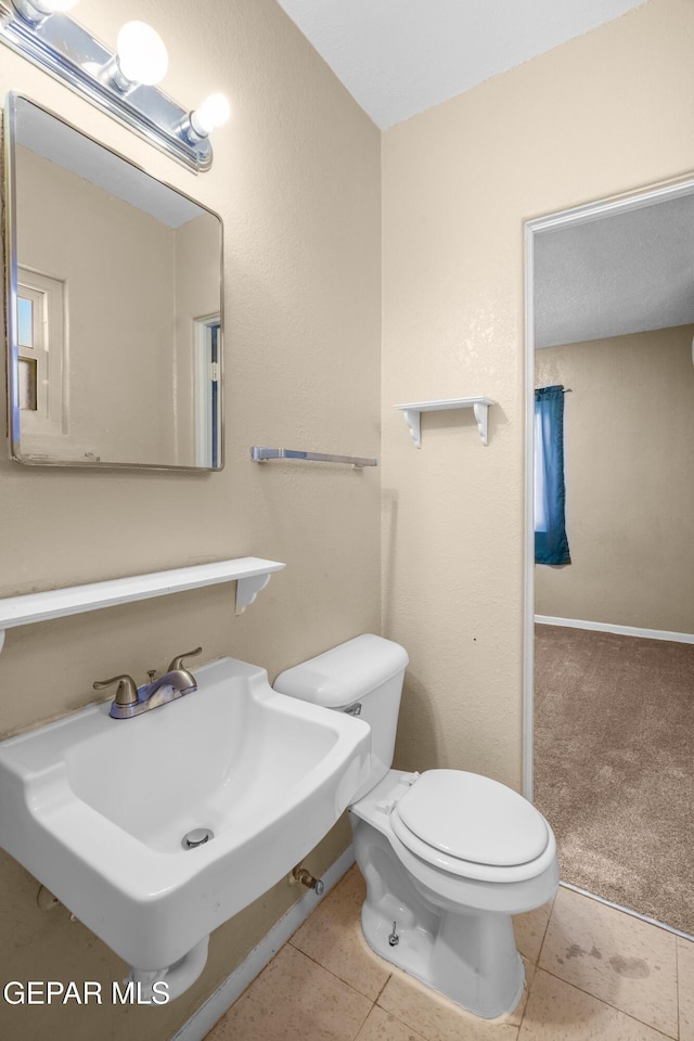 half bathroom featuring tile patterned flooring, a sink, and toilet