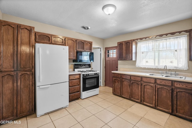 kitchen with white appliances, light countertops, a sink, and a textured ceiling